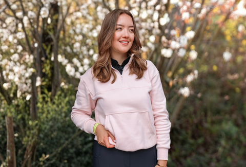 Frau, die einen hellrosa Half-Zip-Pullover ROSÉ von EquiAttire trägt.